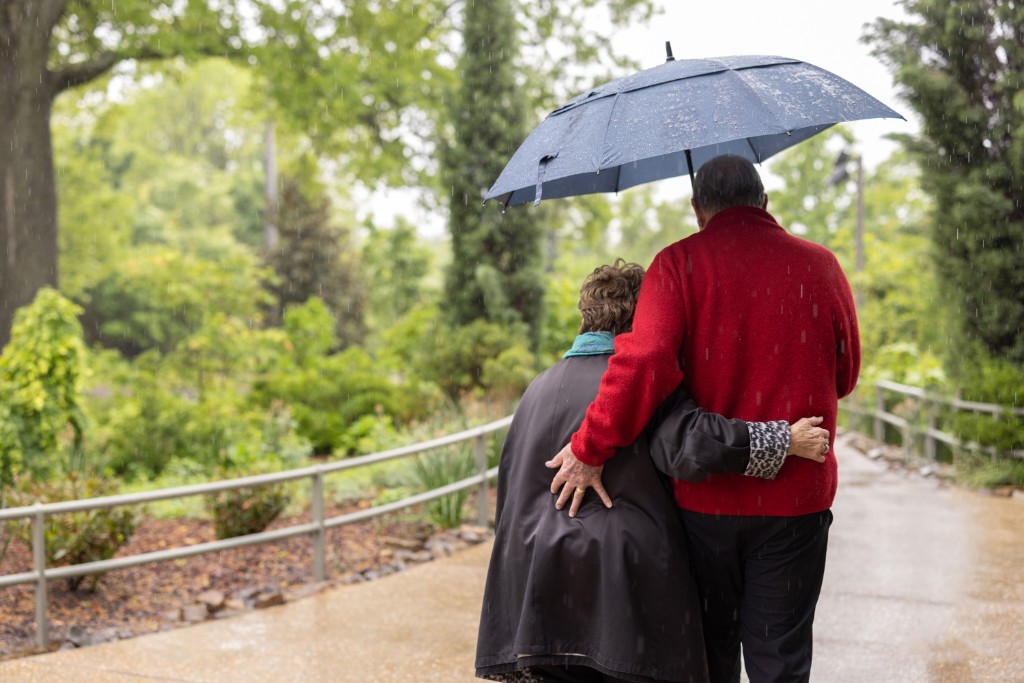 Elderly couple walking together in the rain with an umbrella